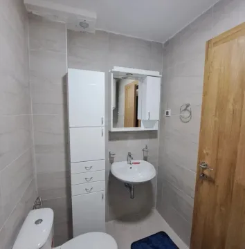 Manje kupatilo obloženo keramičkim pločicama sa umivaonikom, ogledalom i WC šoljom. - image 7