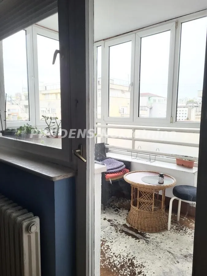 Enclosed balcony with a small table and chairs.