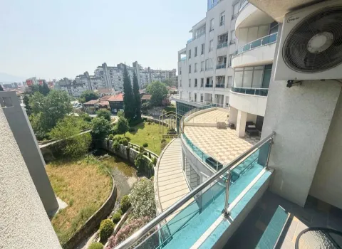 View from the balcony overlooking surrounding buildings and green area. - image 11