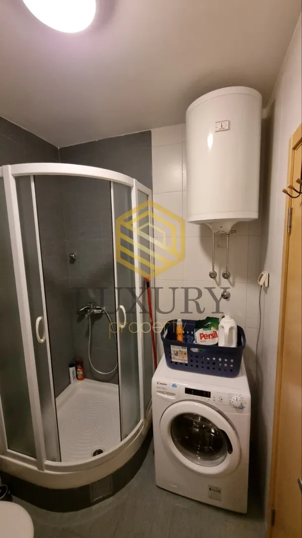 Smaller bathroom with a shower cabin, water heater, and washing machine.