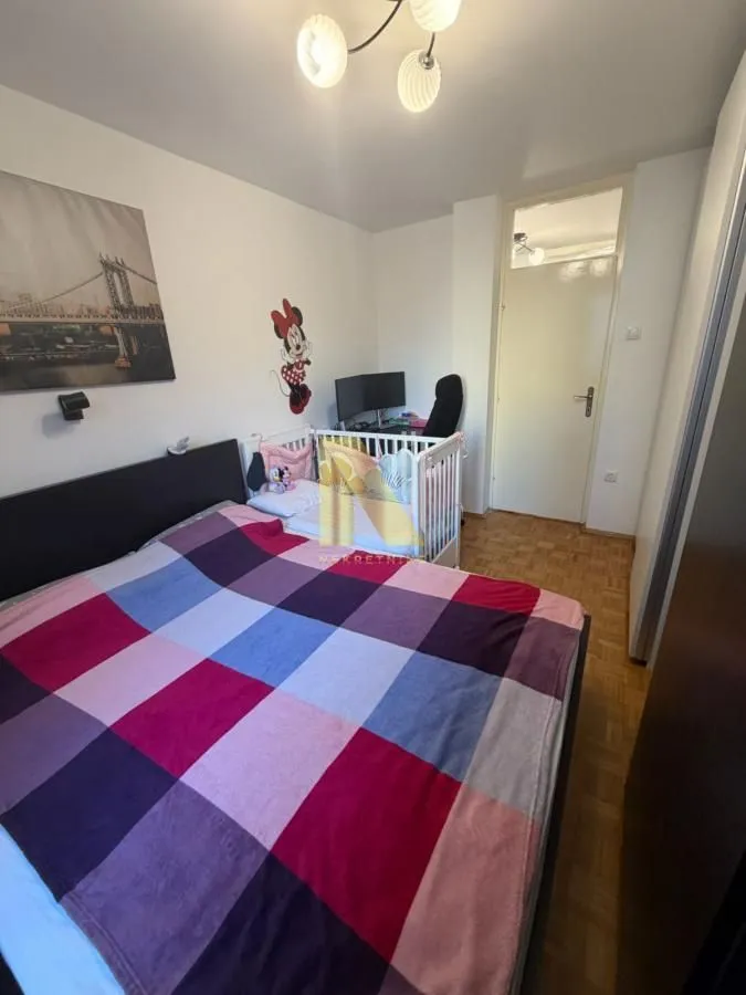 Spavaća soba sa bračnim krevetom i dečijim krevetcem.