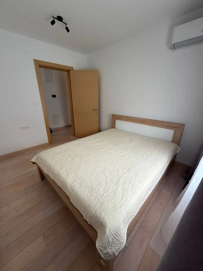 Namještena spavaća soba sa bračnim krevetom i drvenim podom.