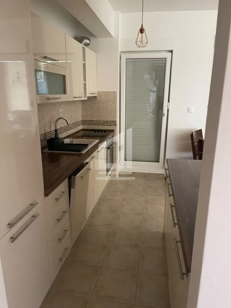 Small kitchen with light cabinets and access to the terrace.