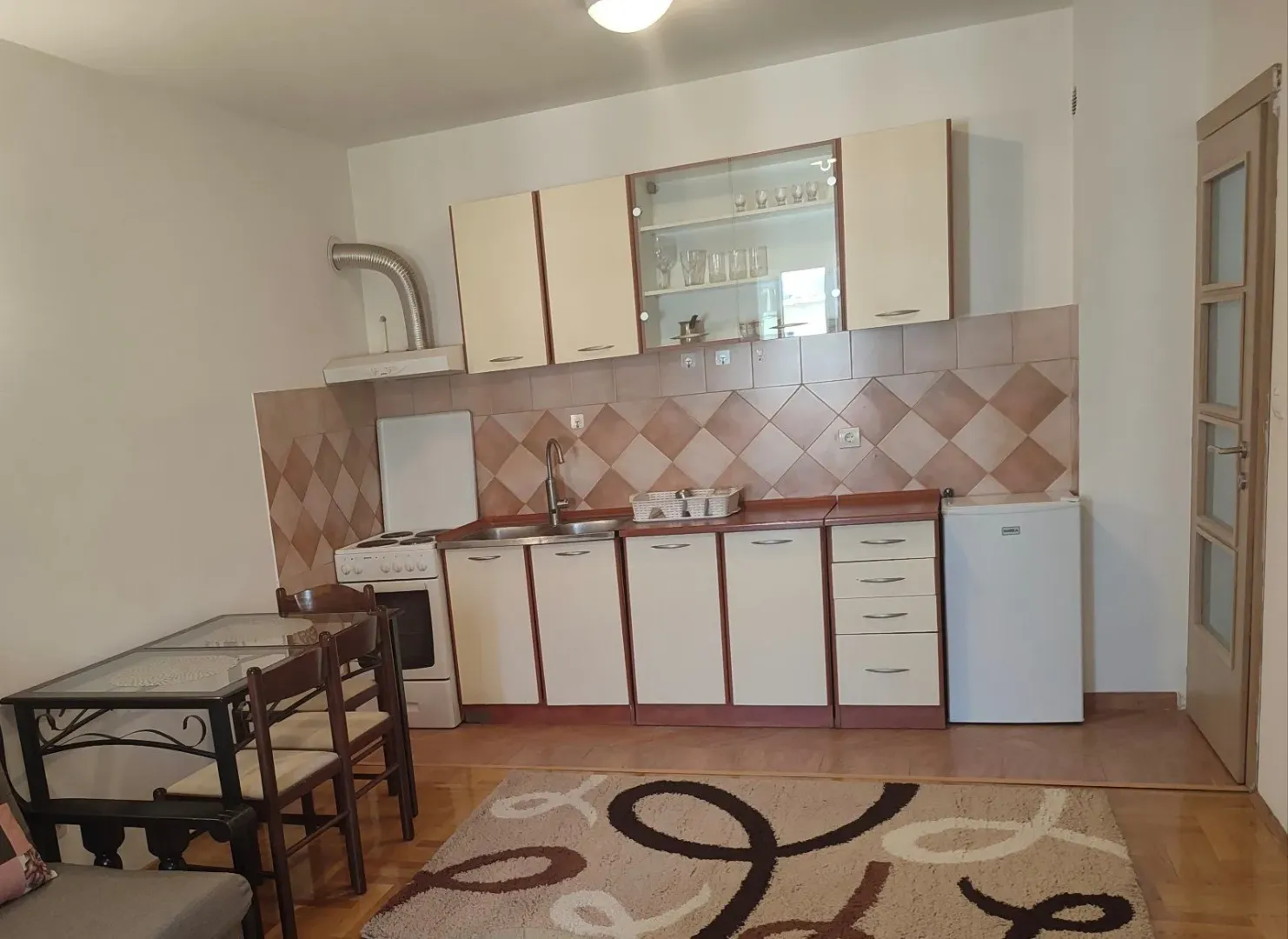 Kuhinja sa trpezarijskim stolom i osnovnim elementima.
