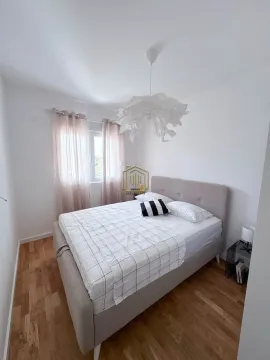 Spavaća soba sa bračnim krevetom, bijelim zidovima i drvenim podom. - image 5