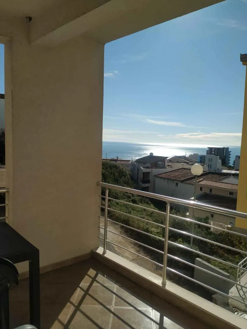 Natkriveni balkon sa metalnom ogradom i pogledom na more.