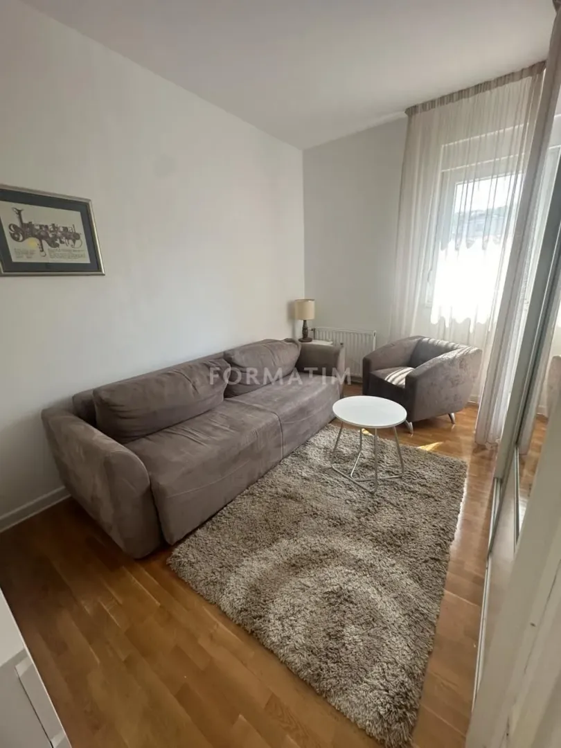 Living room with a sofa, armchair, coffee table, and parquet flooring.