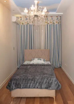 Children's bedroom with a bed, chandelier, and blue-and-white curtains. - image 11