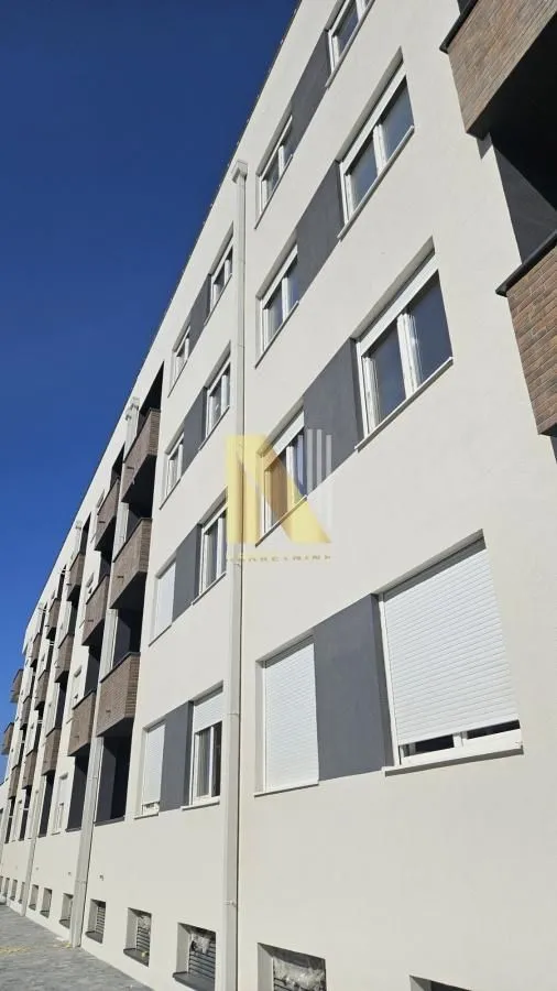 Pogled na spoljašnjost stambene zgrade sa prozorima i roletnama.