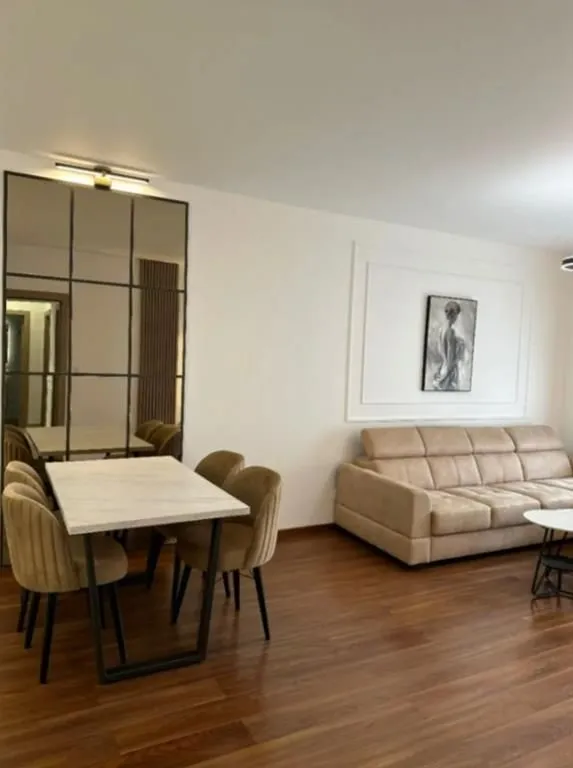 Living room with a sofa, dining table, and a large mirror.