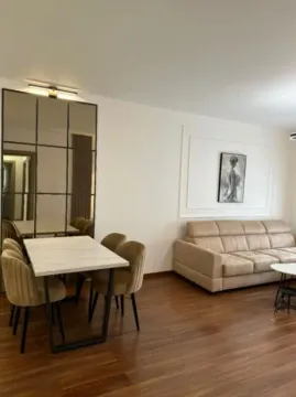 Living room with a sofa, dining table, and a large mirror. - image 3