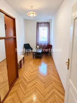 Dugačka dnevna soba sa drvenim parketom, nameštajem i prozorom na kraju prostorije. - image 5