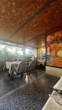 Covered terrace with tables, chairs, and an artwork on the wall. - image 2