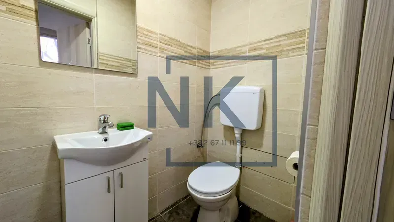 Small tiled bathroom with a washbasin and a toilet.
