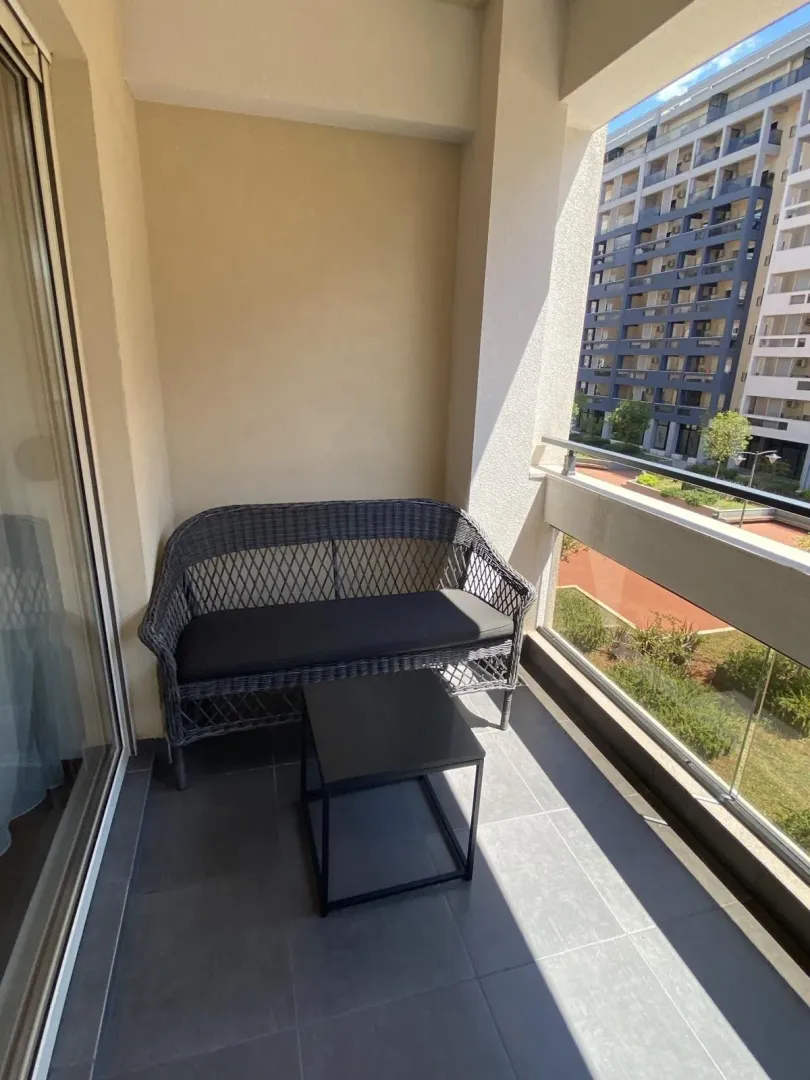 Balkon sa pletenom garniturom za sjedenje i malim stolom.