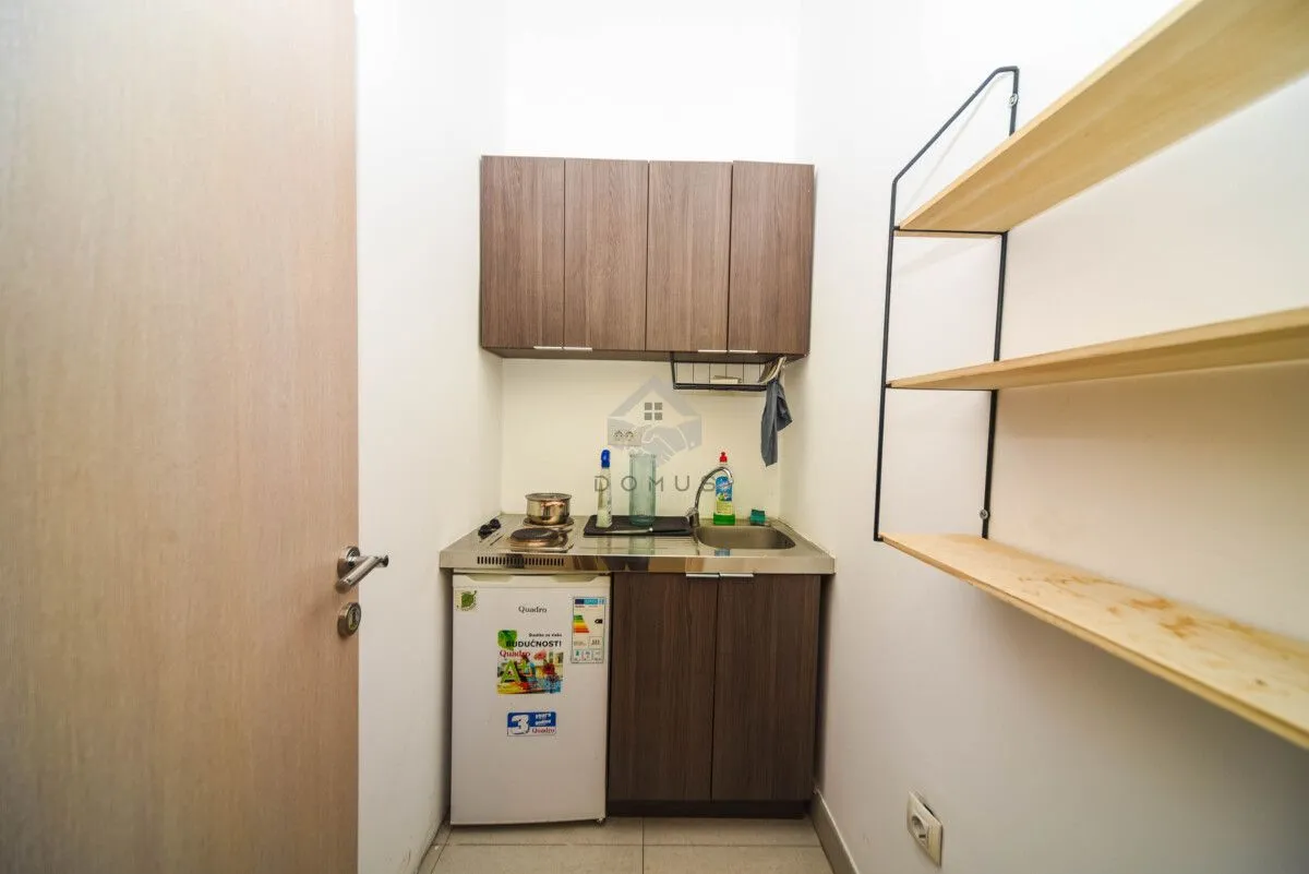 Small kitchenette with a sink, built-in cabinetry, and a refrigerator.