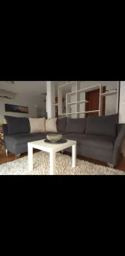 Living room with a sectional sofa, white coffee table, and rug. - image 4