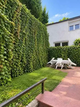 Green yard with a table, chairs, and lawn next to the house facade. - image 15