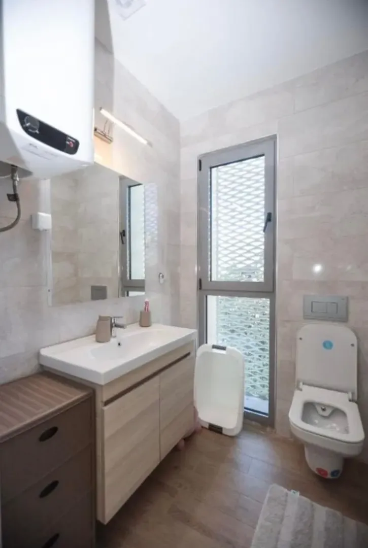Small bathroom with a sink, toilet, and window.