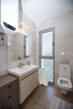 Small bathroom with a sink, toilet, and window. - image 14