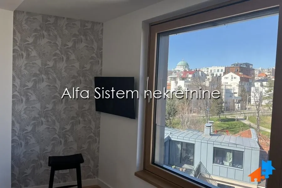 View through the window from a room with a TV on the wall.