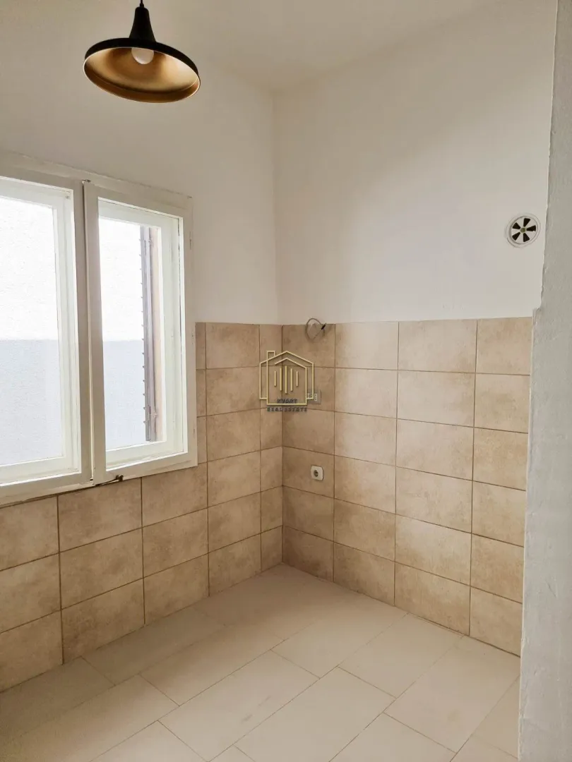 Empty kitchen with wall tiles and a window.