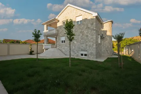 Exterior of the stone-clad house with a landscaped yard and lawn. - image 12