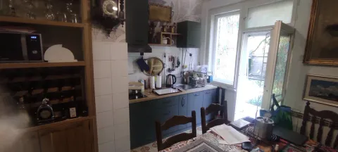 Kuhinja sa tamnim elementima i trpezarijskim stolom u prvom planu. - image 10