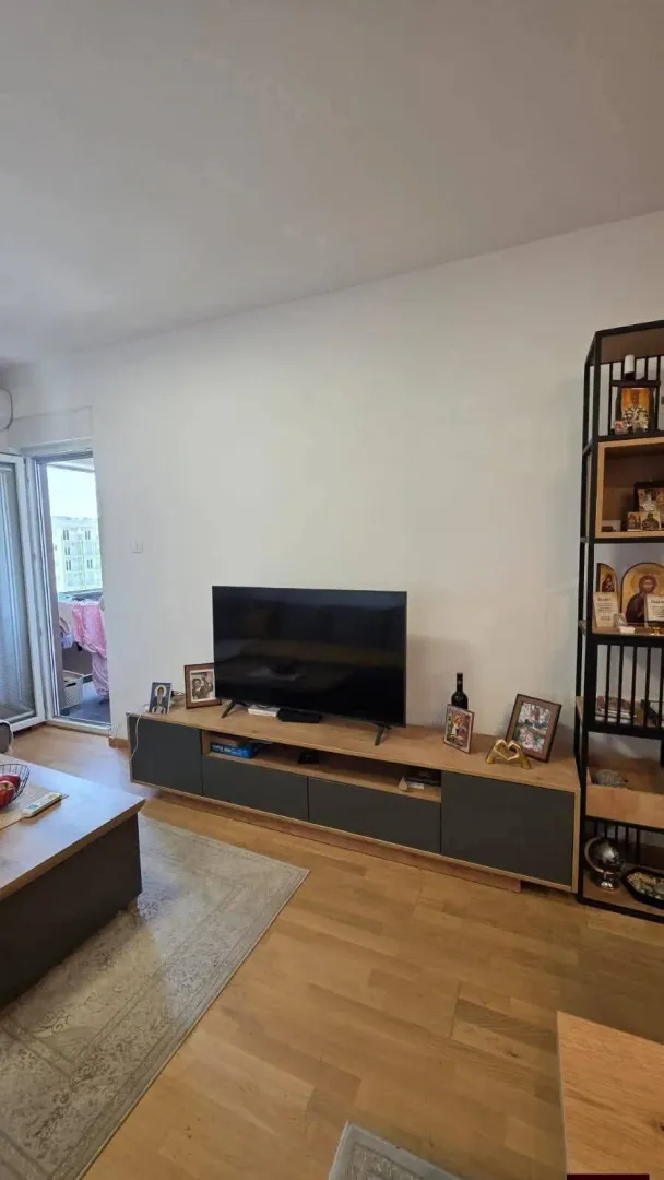 Dnevna soba sa TV komodom i policom.