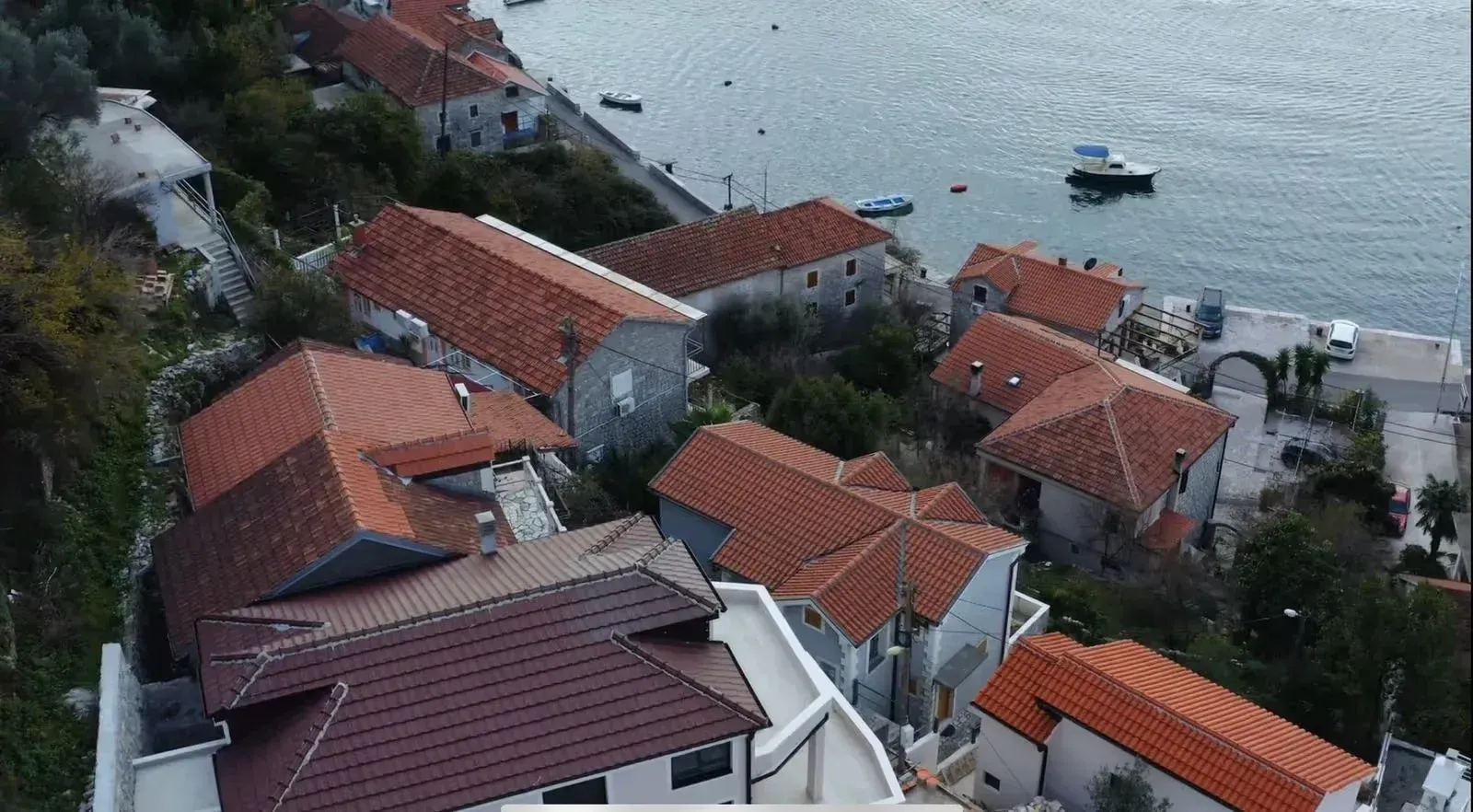 Pogled iz vazduha na mediteranske kuće sa crvenim krovovima u blizini mora.