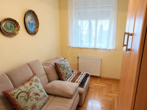 Manja dnevna soba sa kaučem, parketom i ukrasnim slikama na zidu. - image 6