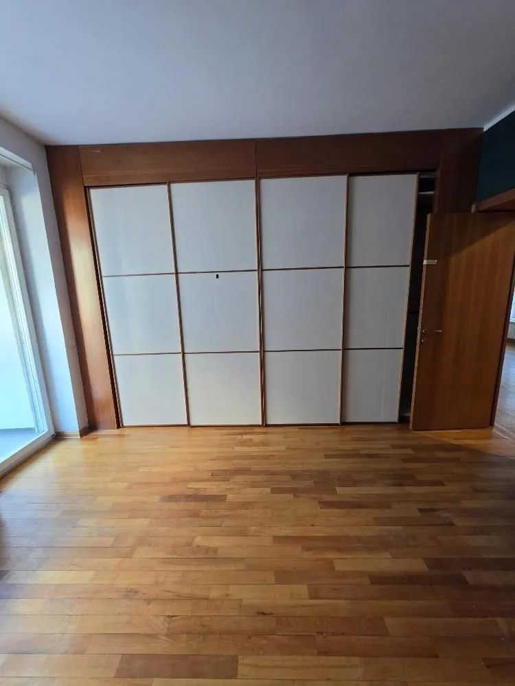 Empty room with a built-in wardrobe and wooden flooring.