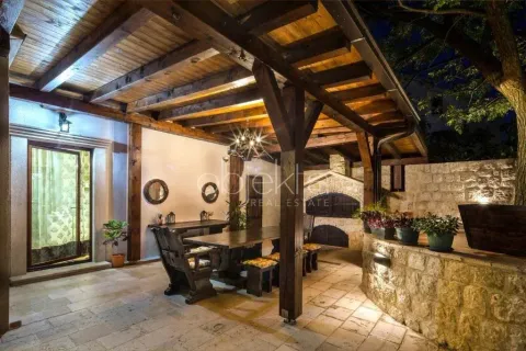 Covered outdoor patio with wooden structure, seating furniture and built-in barbecue at night. - image 8