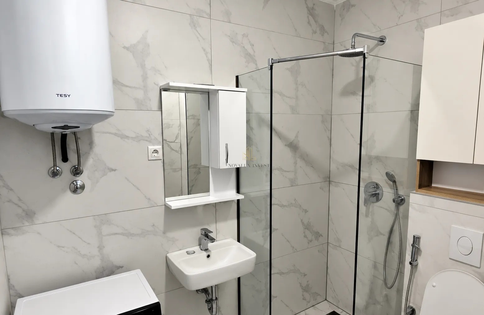Moderno opremljeno kupatilo sa tuš kabinom, umivaonikom i bojlerom.