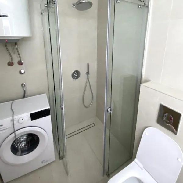 Small bathroom with a shower cabin, toilet, and washing machine.