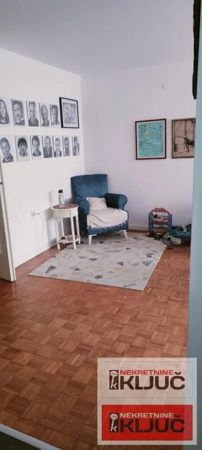Manji dio dnevne sobe sa plavom foteljom i parketom na podu.