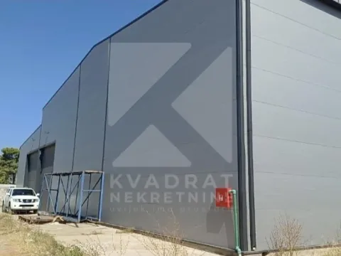 View of the exterior of an industrial building with a metal facade and yard. - image 3