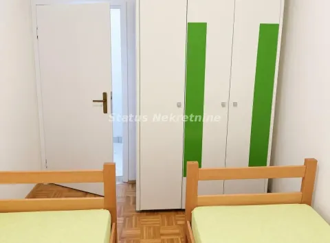 Spavaća soba sa dva drvena kreveta i belim ormanom. - image 8