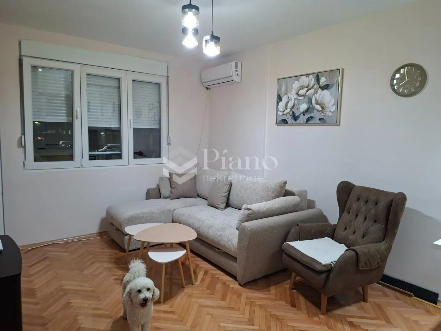Living room with a sofa, an armchair, and parquet flooring.