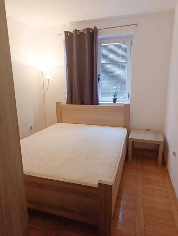 Spavaća soba sa bračnim krevetom, noćnim stočićem i prozorom.