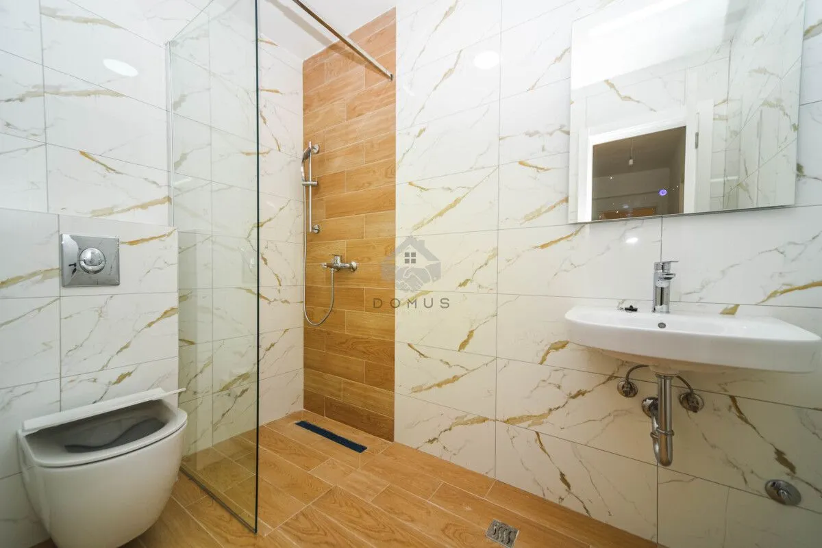 Moderne kupatilo sa tuš kabinom, umivaonikom i ugradnom wc šoljom.
