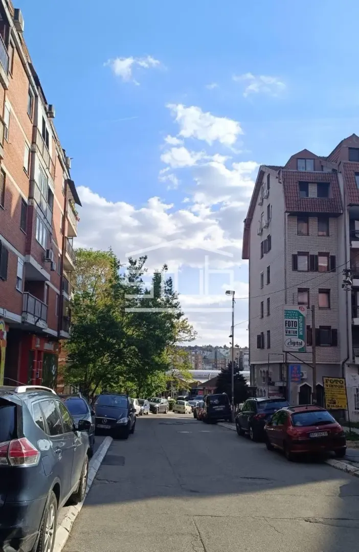View of the street with parked cars and surrounding buildings.