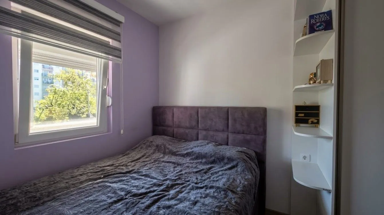 Small bedroom with a double bed, window, and built-in shelving.