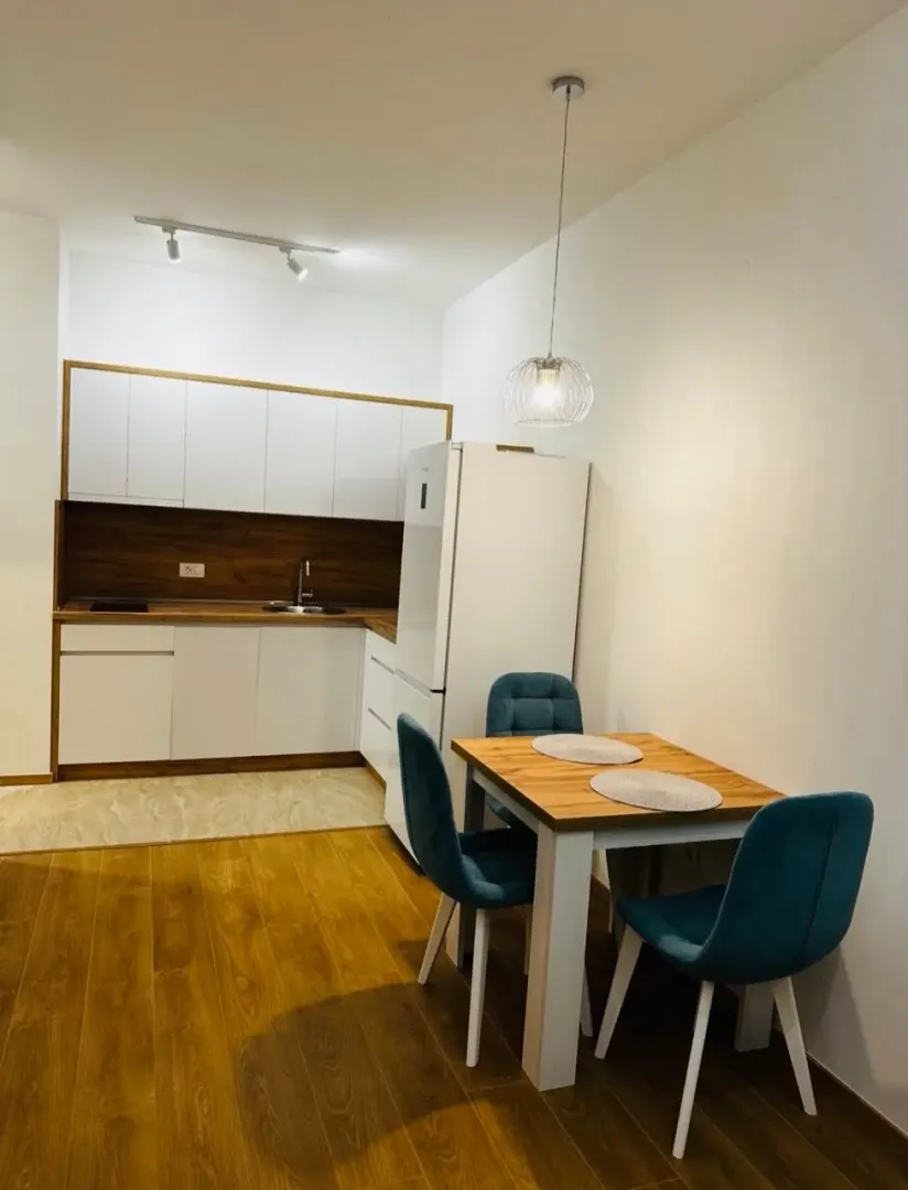 Kitchen with a dining table and blue chairs in a modern apartment.