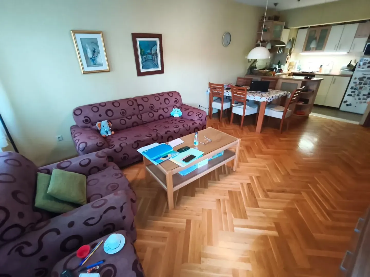 Dnevni boravak sa garniturom, stočićem i trpezarijom u pozadini.