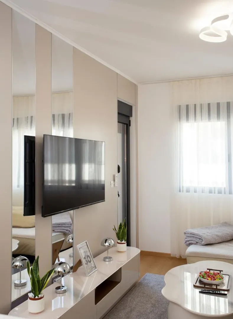 Dnevna soba sa TV-om montiranim na zid i modernim namještajem.