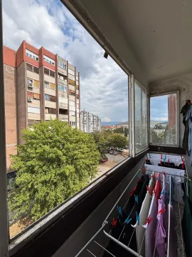 Zastakljeni balkon sa sušilicom za veš i pogledom na naselje. - image 3