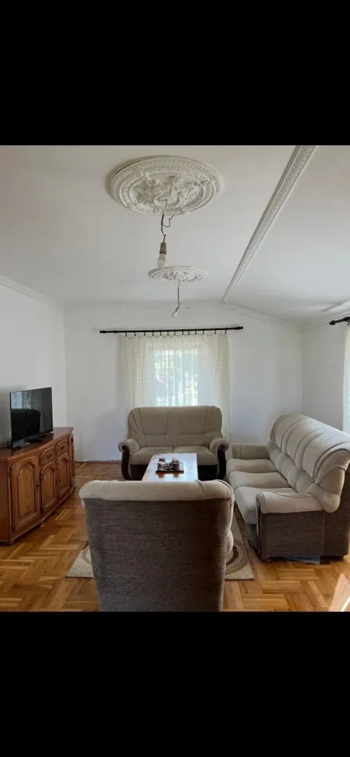 Living room with seating furniture, wooden cabinet, and parquet flooring.