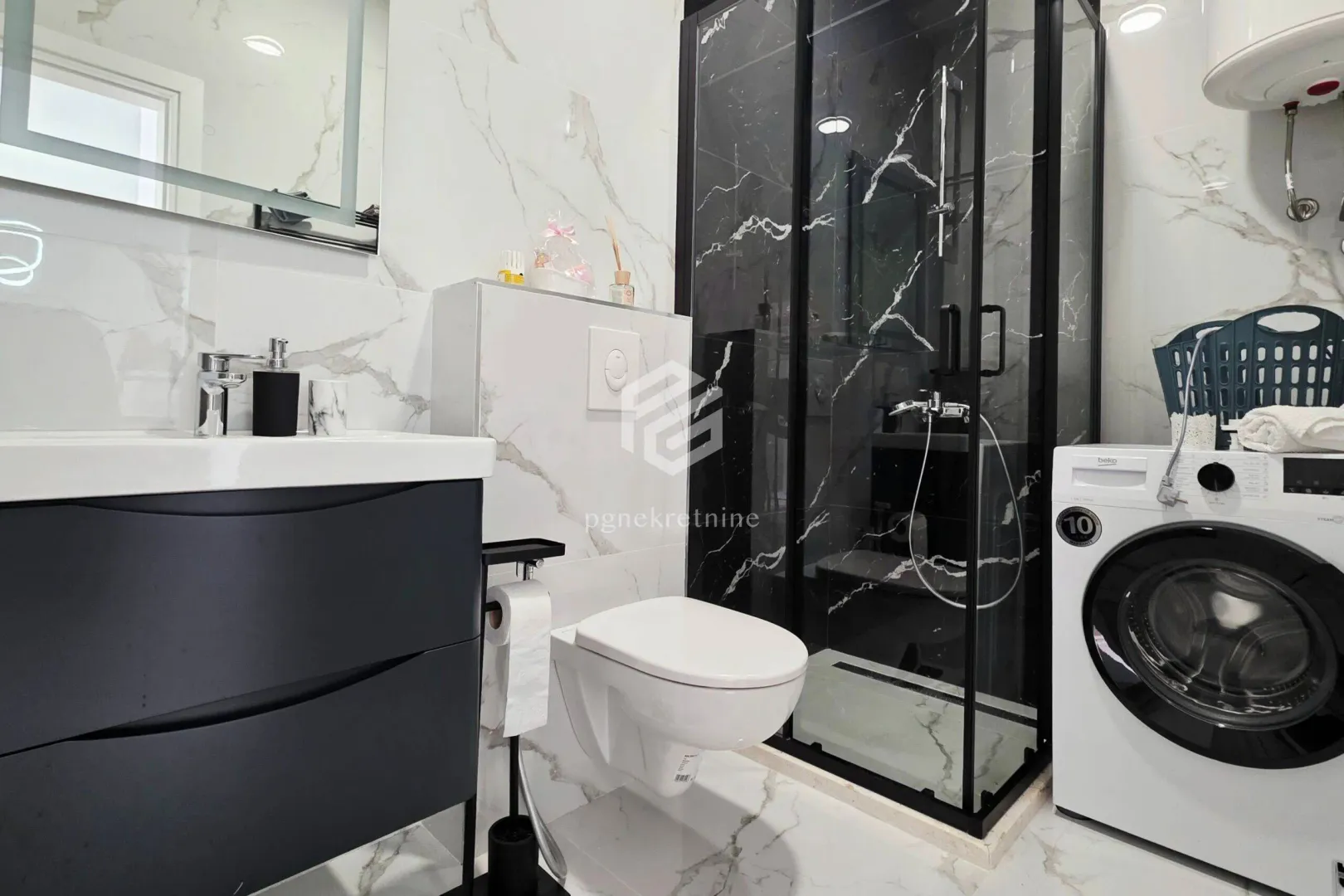 Modernly equipped bathroom with a shower cabin, washbasin, and washing machine.