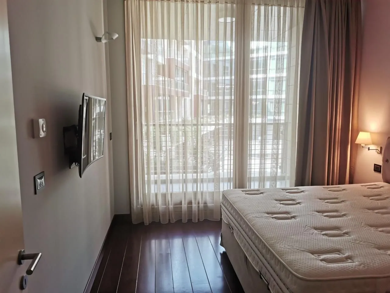 Simple bedroom with a TV and a large window.